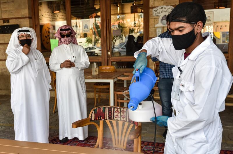 A latex glove-and-mask-clad worker sanitises a table for clients at a cafe in Saudi Arabia's capital Riyadh, as the country begins to re-open following the lifting of a lockdown.  AFP