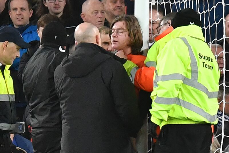 Stewards attempt to release Louis McKechnie, an activist from Just Stop Oil, who attached himself to the goalpost during a football match in Liverpool. AFP