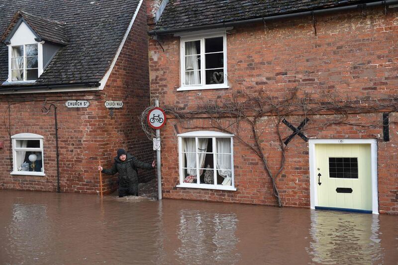 A man wades through in flood water as he passes houses in Church Street in Tenbury Wells, after the River Teme burst its banks in western England after Storm Dennis caused flooding across large swathes of Britain.   AFP