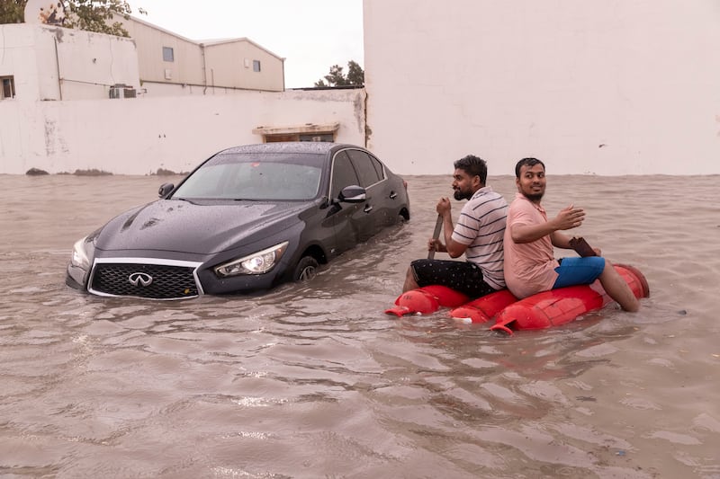 People paddle their way through floodwater in Al Quoz, Dubai, after torrential rain in the region. Antonie Robertson / The National