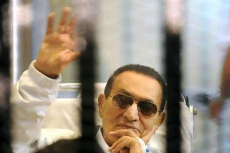 Hosni Mubarak waves to his supporters from behind bars as he attends a hearing in his retrial on Saturday. AP Photo