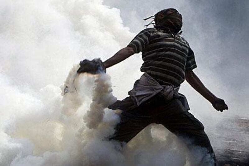 A protester throws a tear gas canister, earlier thrown by riot police, during clashes near Tahrir Square yesterday.