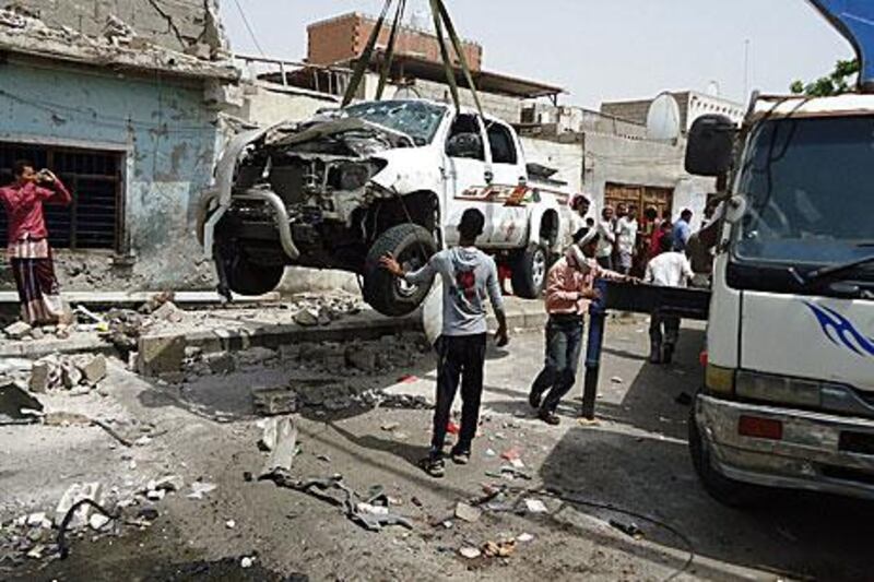 Yemenis remove a destroyed car that was damaged in the suicide attack that killed Yemeni army Major General Salem Ali Qatan in Aden. AFP PHOTO