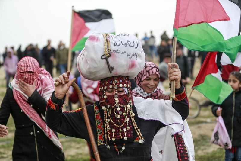 Palestinian protesters wave national flags during a demonstration marking the first anniversary of the "March of Return" protests, near the border with Israel east of Gaza City on March 30, 2019. This marks the first anniversary of the often violent weekly border demonstrations in which around 200 Palestinians and an Israeli soldier have been killed, coming just 10 days before a keenly contested general election in Israel. The border protests peaked in May 2018, when Israeli forces shot dead at least 62 Palestinians in a single day in clashes over the transfer of the US embassy to Israel to the disputed city of Jerusalem. / AFP / ANAS BABA
