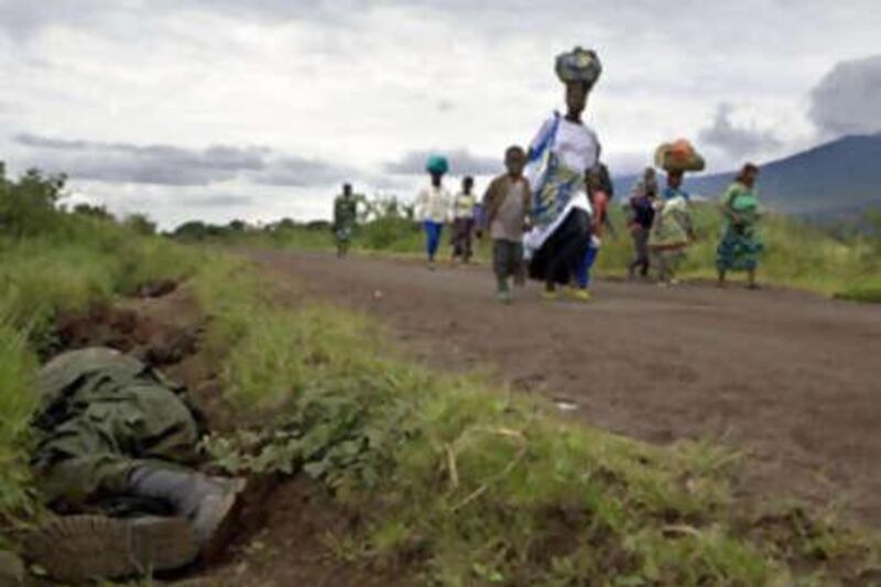 Displaced people returning to their homes in rebel-held territory outside of Goma walk past the body of a Congolese soldier.