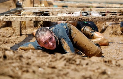 FILE PHOTO: A woman crawls through an obstacle called "kiss of mud" during the Tough Mudder untimed hardcore endurance event in Arnsberg, Germany June 1, 2019.  REUTERS/Wolfgang Rattay/File Photo