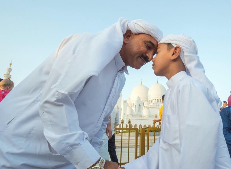 Abu Dhabi, UNITED ARAB EMIRATES - A father and his son greet each other after performing morning prayers on the first day of Eid-Al Fitr at the Sheikh Zayed Grand Mosque.  Leslie Pableo for The National