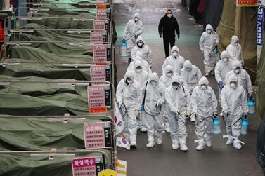  Market workers wearing protective gear spray disinfectant at a market in the southeastern city of Daegu in South Korea. AFP