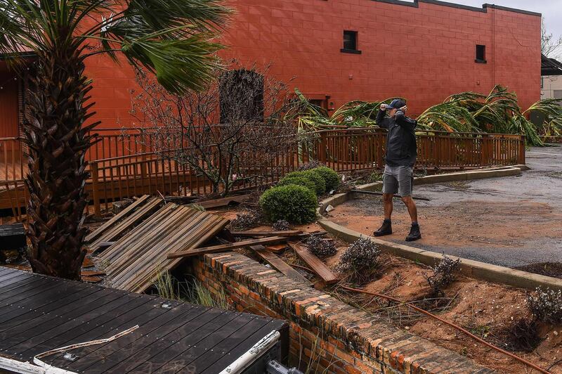 A man holds his hat in a strong wind during Hurricane Sally in downtown Pensacola, Florida.  AFP