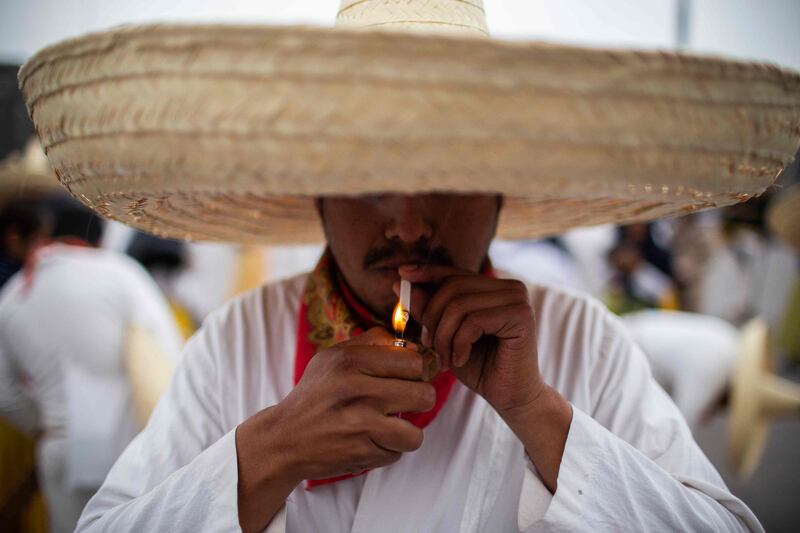 A man wearing a traditional hat has a smoke break during the commemoration of the 112th anniversary of the Mexican Revolution at Zocalo Square, Mexico City. AFP