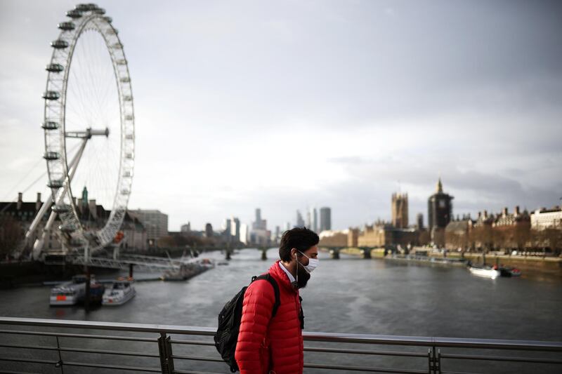 A man wearing a protective face mask walks along the Golden Jubilee Bridge in London. Reuters