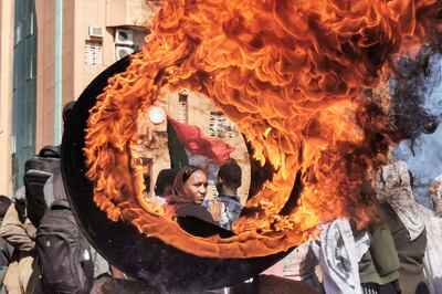 A demonstrator looks on from behind a flaming tire during a protest in Omdurman, Sudan. AFP