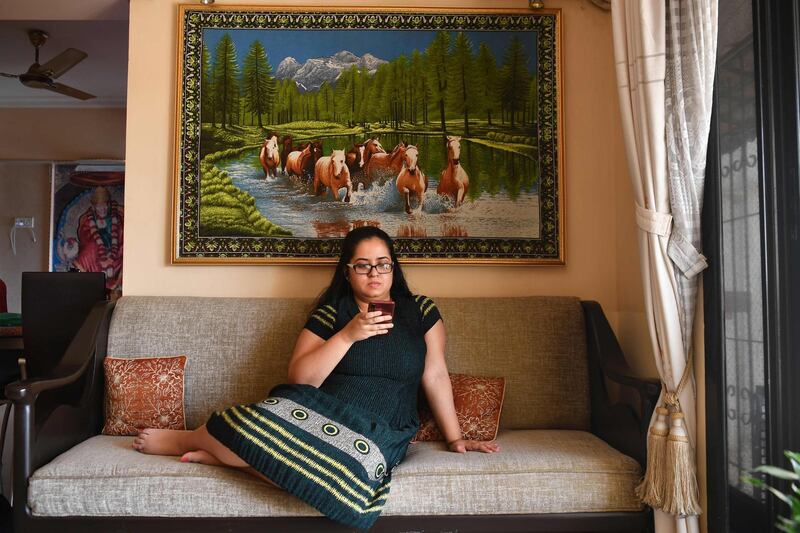 This picture taken on March 23, 2020 shows human resources professional Diya RoyChowdhury listening to music on her mobile phone while working from home in Mumbai, during a partial lockdown as a preventive measure against the spread of the COVID-19 novel coronavirus. / AFP / Indranil MUKHERJEE
