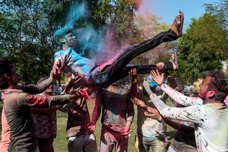 Students from Lalbhai Dalpatbhai (LD) College of Engineering throw in the air a fellow as they celebrate 'Holi', the Hindu spring festival, with eco-friendly coloured powders in Ahmedabad on March 7, 2020. Holi, the popular Hindu spring festival of colours is observed in India and across countries at the end of the winter season on the last full moon of the lunar month. AFP