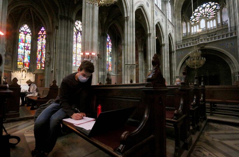 Students attend online in the neo-gothic Votivkirche in Vienna, Austria. The church was converted into an auditorium for the University of Vienna. AP Photo