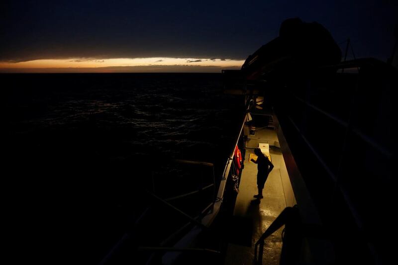 A crew member stands on the deck of the Malta-based NGO Migrant Offshore Aid Station (MOAS) ship Phoenix after sunset in the central Mediterranean ininternational waters off the coast of Libya. Darrin Zammit Lupi / Reuters