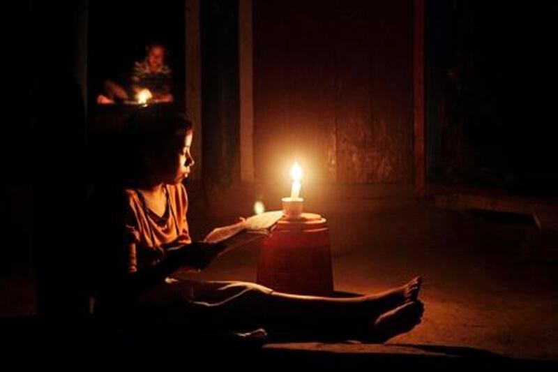 A young Indian girl reads a book by candle light during a regular load shedding in Mainakhurung on the outskirts of Gauhati, India, Wednesday, Aug. 1, 2012. Factories and workshops across India were up and running again Wednesday, a day after a major system collapse led to a second day of power outages and the worst blackout in history leaving an estimated 620 million people without electricity. (AP Photo/Anupam Nath)