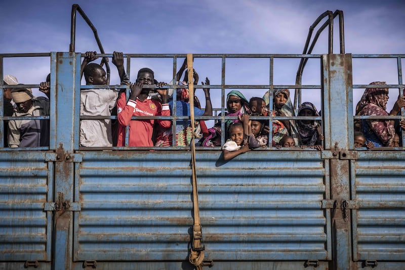 Refugees who have fled from the war in Sudan stand on a truck arriving at a Transit Centre
