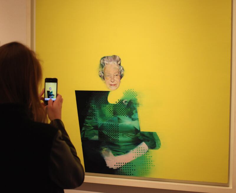 A woman photographs a painting by artist Justin Mortimer, entitled 'The Queen', in the National Portrait Gallery, London, in 2012. Getty Images