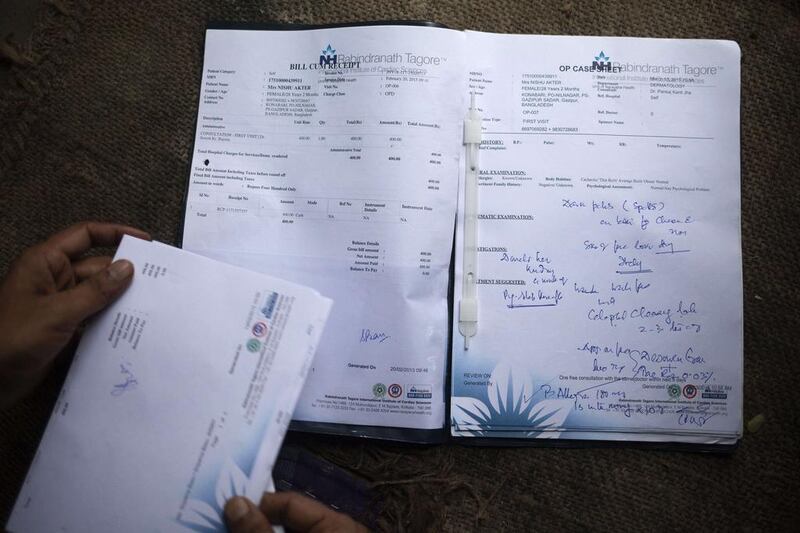 Rawshan Ara, shows her medical records — which are in another name — in the village of Kalai. Suvra Kanti Das / AFP