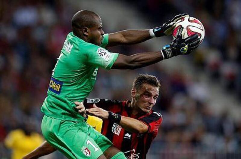 Lille's Nigerian goalkeeper Vincent Enyeama, left, catches the ball in front of Nice forward Eric Bautheac during a French Ligue 1 football match on September 24, 2014 at the "Allianz Riviera" stadium in Nice, southeastern France. AFP PHOTO / VALERY HACHE