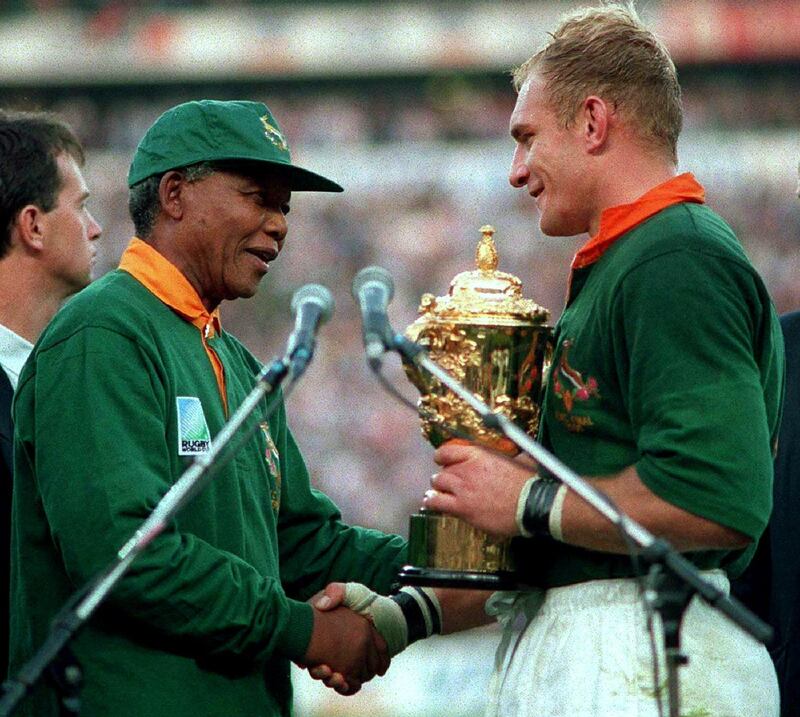 South African President Nelson Mandela (R) hands over the William Webb Ellis Cup to Springbok captain Francois Pienaar after his team defeated New Zealand in the Rugby World Cup final June 24