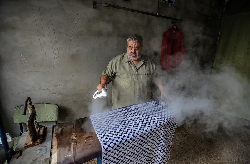 Abu Ghabin steam-irons the checkered cotton cloth he normally uses to make the traditional Palestinian keffiyeh at his workshop in Gaza City.   EPA