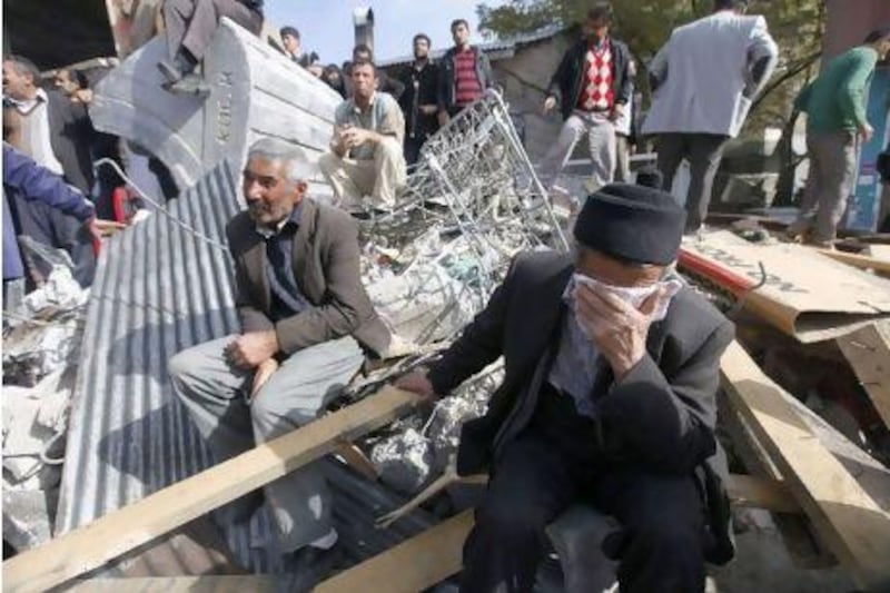 Survivors sit amid rubble in the town of Ercis, where at least 80 apartment buildings collapsed in Sunday's earthquake.