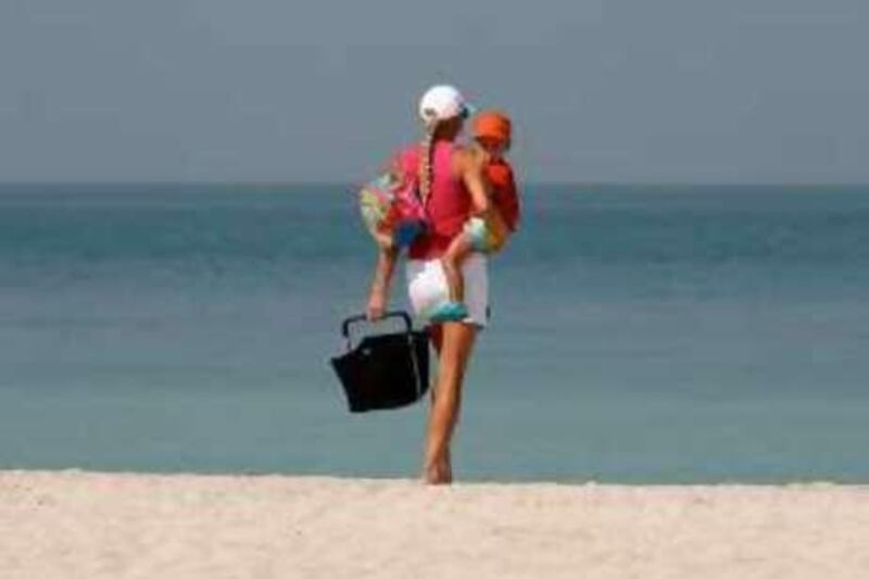 
DUBAI, UNITED ARAB EMIRATES Ð Oct 12: One of the beach goer walking on the beach with her baby at Umm Suqueim area of Dubai. (Pawan Singh / The National) *** Local Caption ***  PS01- UMM SUQUEIM.jpgHH25OC1 - UMM SUQUEIM.jpg