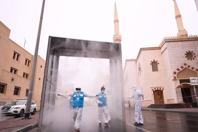 Health volunteers pass through a sterilisation chamber installed to disinfect residents entering and leaving the Naif area in the Gulf emirate of Dubai during the COVID-19 coronavirus outbreak, on April 15, 2020.  / AFP / KARIM SAHIB
