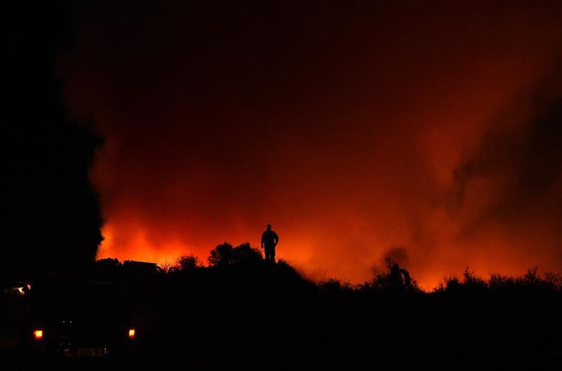 A firefighter is silhouetted while watching flames approach Loma Prieta peak in California’s Santa Cruz Mountains. The Loma Prieta Fire has charred more than 1,000 acres and burned multiple structures in the area. Josh Edelson / AFP