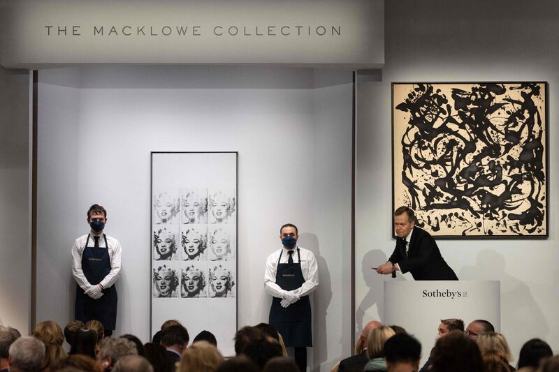 Oliver Barker of Sotheby's leads the Macklowe Collection auction. Seen here are Andy Warhol's 'Nine Marylins', left, which sold for $47.3m, and Jackson Pollock's 'Number 17' (1951), right. AFP