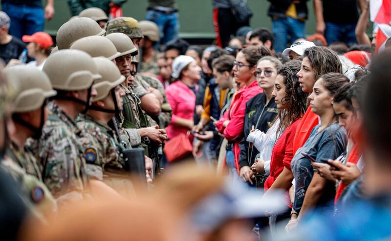 Female protesters stand in a line before Lebanese army soldiers during a demonstration on the seventh day of protest against tax increases and official corruption, in Zouk Mosbeh, north of the capital Beirut, on October 23, 2019. The almost one-week-old massive street protests in Lebanon, sparked by a tax on messaging services such as WhatsApp, have morphed into a united condemnation of a political system seen as corrupt and beyond repair. / AFP / JOSEPH EID
