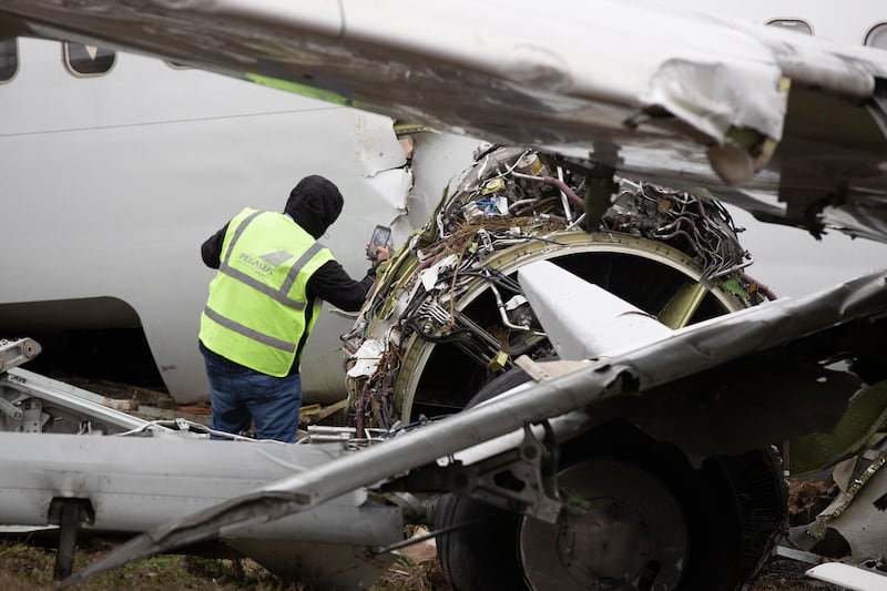Firefighters and Pegasus Airlines crew inspect the wrecked plane after a Pegasus Airlines plane has skidded off the Sabiha Goekcen airport runway in Istanbul.  EPA