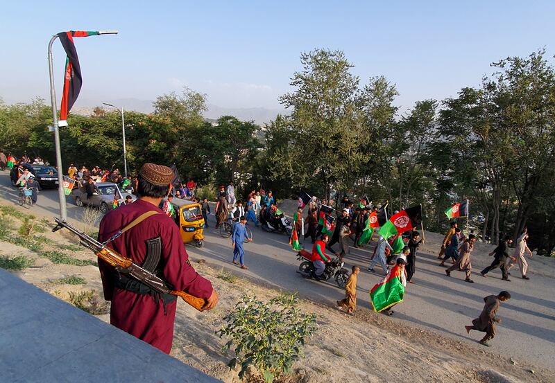 A Taliban fighter watches as people take part in a protest. Photo by Muhammad Imran