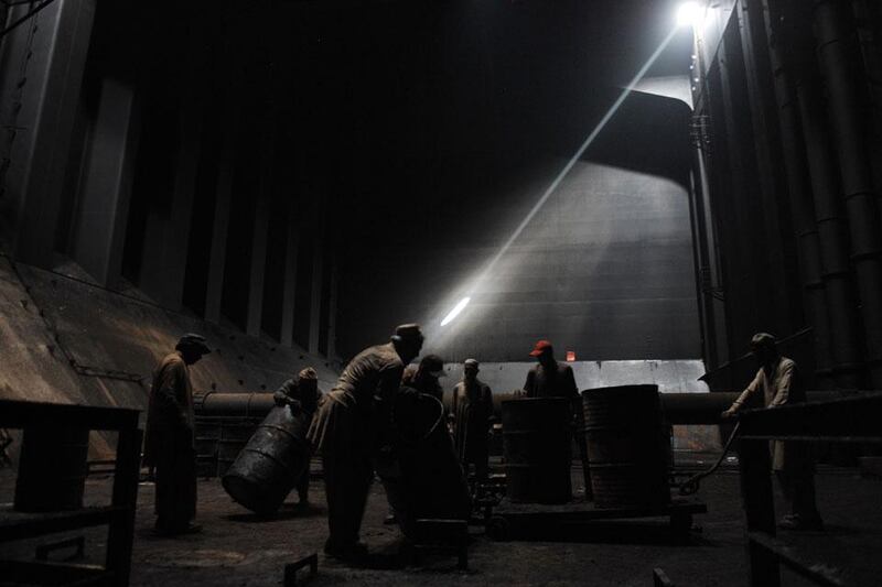 Roll out the barrel: workers remove oil barrels from inside the hull of a vessel being dismantled in Geddani.