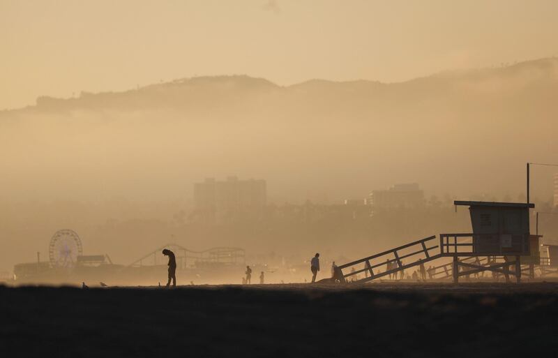 People gather as the Sun sets on the mostly empty Venice Beach, California.  AFP