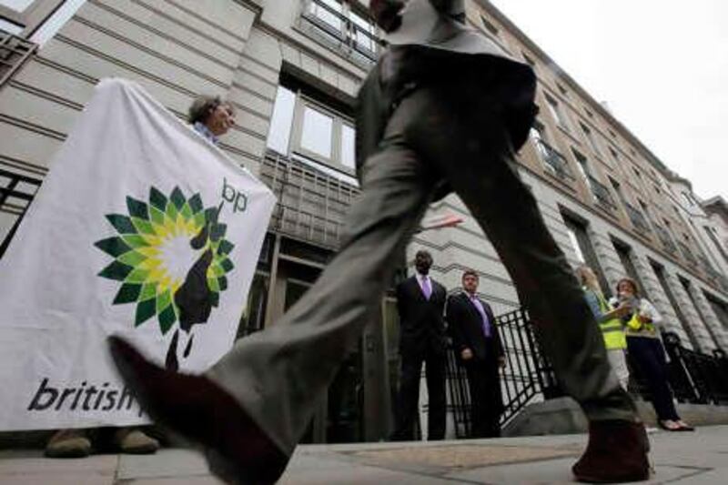 A protester from the Greenpeace group holds a banner with BP company's altered logo with 'oil'  spilled on it and  the words 'British Polluters' alongside it outside the entrance to the BP headquarters in central London Thursday May 20, 2010. Protesters also climbed on a balcony of the building and attached a  flag, similar to the banner to protest the oil spill in the Gulf of Mexico. (AP Photo/Lefteris Pitarakis)