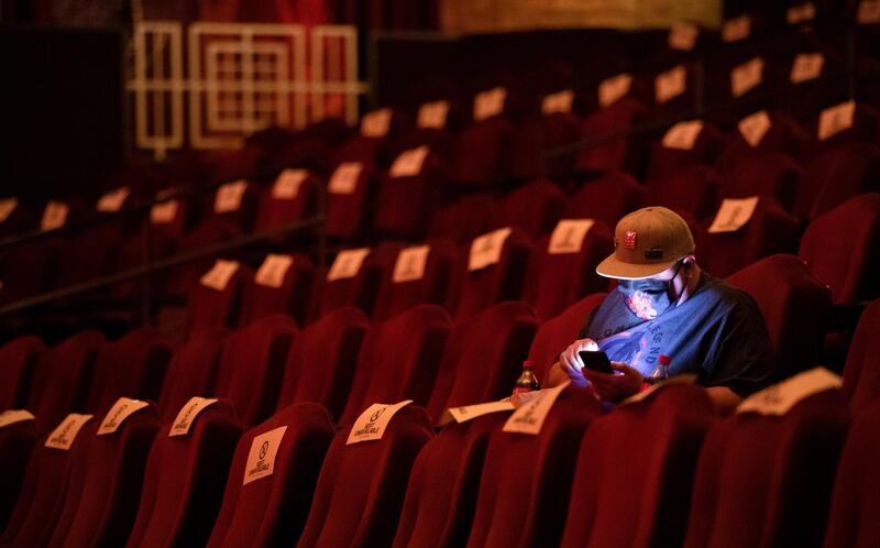 A moviegoer uses his mobile phone while waiting for the movie "Godzilla vs. Kong" on the reopening day of the TCL Chinese theatre in Los Angeles, California, US. Reuters