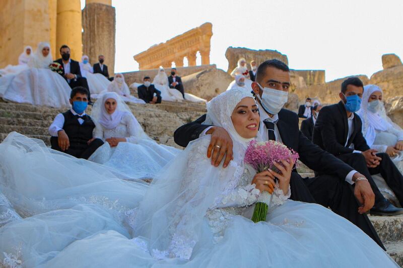 Lebanese couples, wearing protective face masks, sit on the steps during a group wedding at the Temple of Bacchus at the historic site of Baalbek in Lebanon's eastern Bekaa Valley. AFP