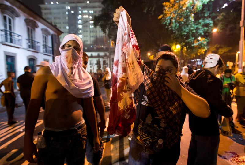 Protesters hold a blood-stained t-shirt of a protester that was shot in the shoulder during a demonstration in Rio de Janeiro, Brazil, Monday, June 17, 2013. Officers in Rio fired tear gas and rubber bullets when a group of protesters invaded the state legislative assembly and threw rocks and flares at police. Protesters massed in at least seven Brazilian cities Monday for another round of demonstrations voicing disgruntlement about life in the country, raising questions about security during big events like the current Confederations Cup and a papal visit next month.  It was not clear who shot the man. (AP Photo/Victor R. Caivano) *** Local Caption ***  Brazil Confed Cup Protests.JPEG-04a8c.jpg