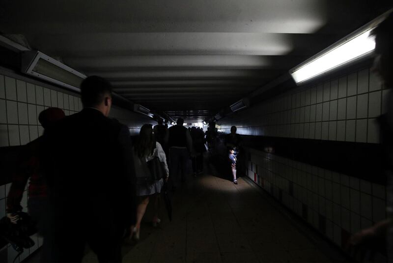 People walk in near darkness at Clapham Junction station during a power cut, in London, Friday, Aug. 9, 2019. London and large chunk of the U.K. were hit with a power cut Friday afternoon that disrupted train travel and snarled rush-hour traffic.U.K. Power Networks, which owns and maintains electricity cables in London and southern England, said a network failure at power supplier National Grid was affecting its customers. (Yui Mok/PA via AP)
