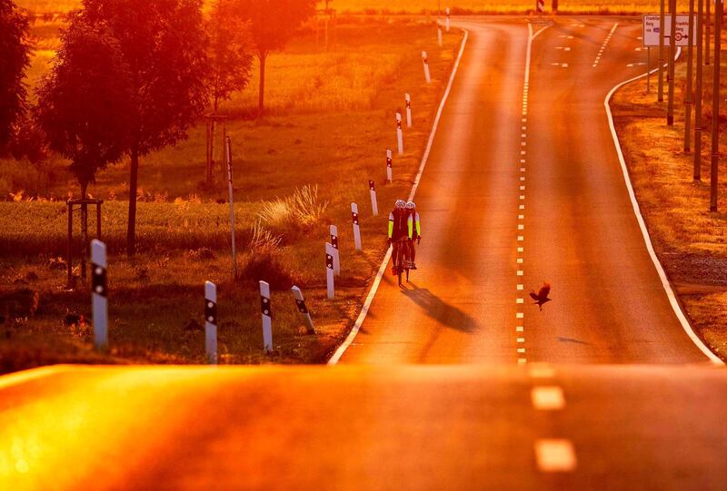 A man and a woman ride their bikes on a land road as the sun rises in the outskirts of Frankfurt, Germany. AP Photo