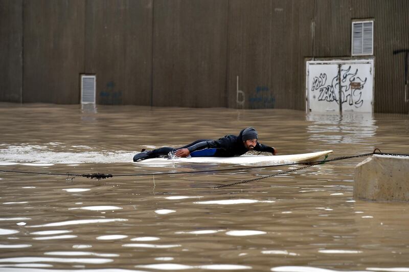 A man uses a paddleboard on a flooded after a heavy downpour on the main road near Rafic Hariri International Airport at the southern entrance of Beirut.  EPA