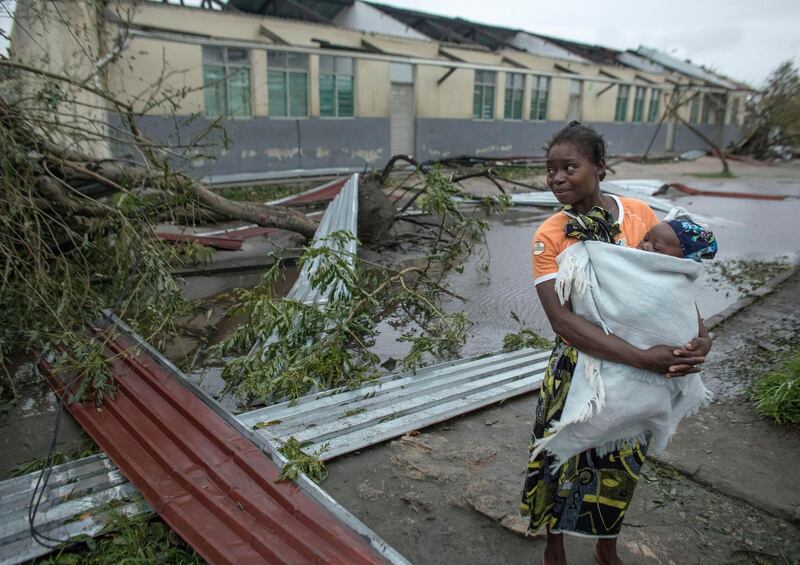 A local resident carries her chilld past debris at  the secondary school used as an emergency shelter for local residents in the village of Inhamizua, Mozambique. CARE/ EPA