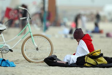 A cyclist clad in hat and sweater takes a break on Kite beach. Chris Whiteoak / The National