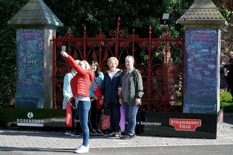 Tourists take photographs next to the original iron gates to Strawberry Field.