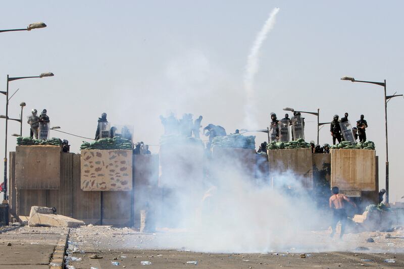 Anti-riot police, standing on barricades, disperse protesters with tear gas, in Baghdad. Reuters