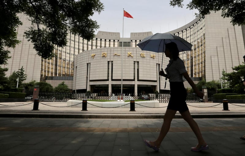 FILE PHOTO: A woman walks past the headquarters of the People's Bank of China (PBOC), the central bank, in Beijing, June 21, 2013. To match Special Report CHINA-RISK/MORTGAGES   REUTERS/Jason Lee/File Photo