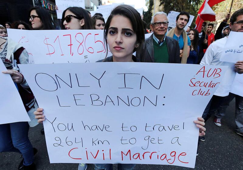 Lebanese protestors hold placards during a demonstration against the ongoing ban on civil unions in the Lebanese capital Beirut on March 1, 2015. Lebanese authorities recognise civil weddings only if they have been registered abroad. Many Lebanese couples travel to neighbouring Cyprus to tie the knot in a civil wedding. The number of Lebanese marrying in Cyprus doubled between 2007 and 2013. AFP PHOTO / STR (Photo by STR / AFP)